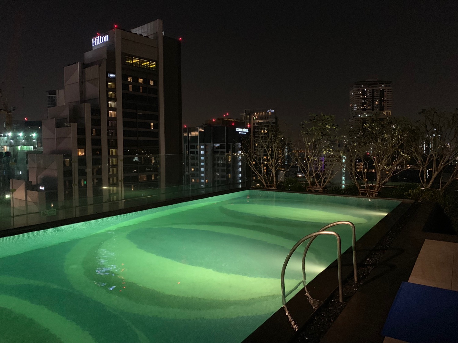 a pool with a railing and a city skyline at night