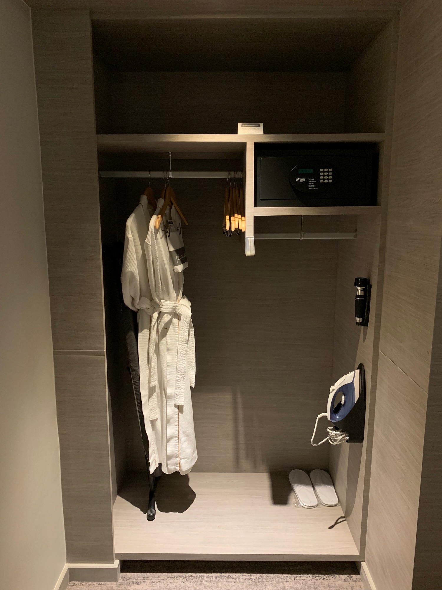 a closet with white bathrobes and a small microwave