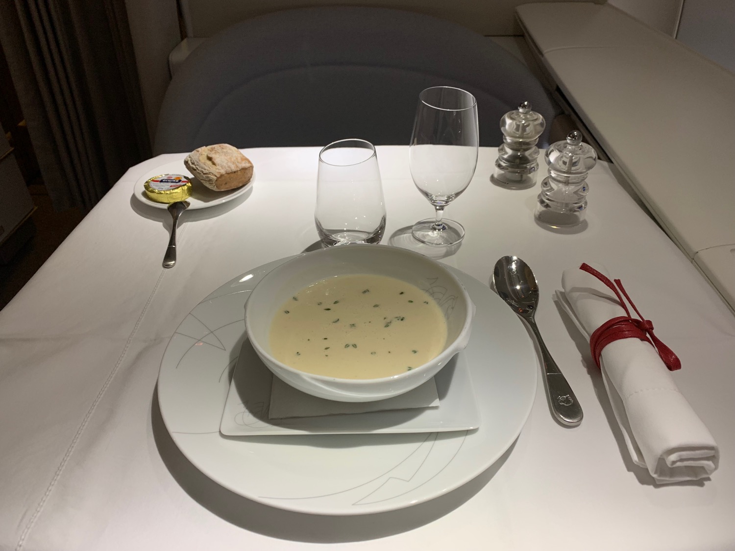 a bowl of soup on a plate with a napkin and fork