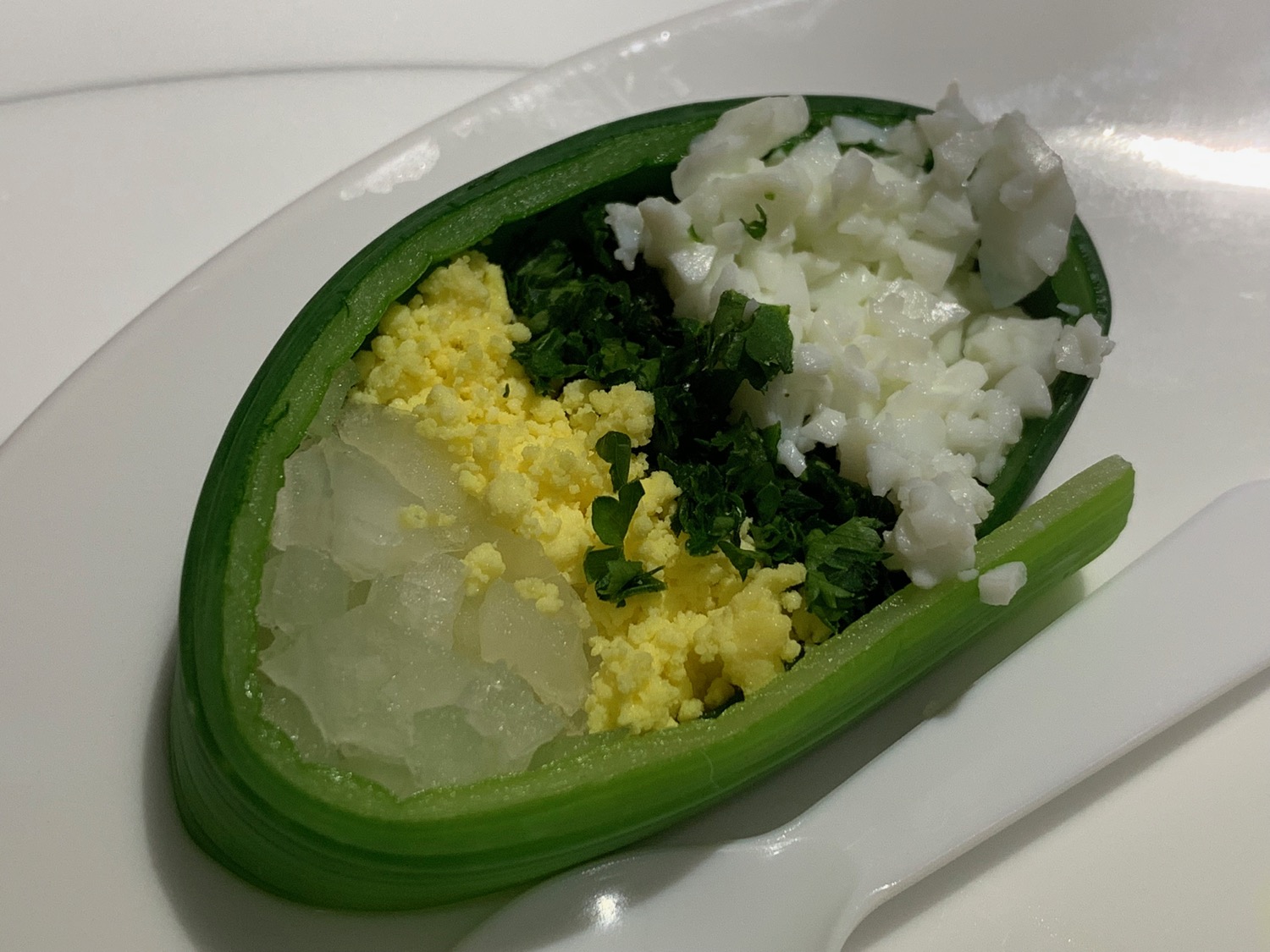 a green pepper with eggs and greens on a white plate