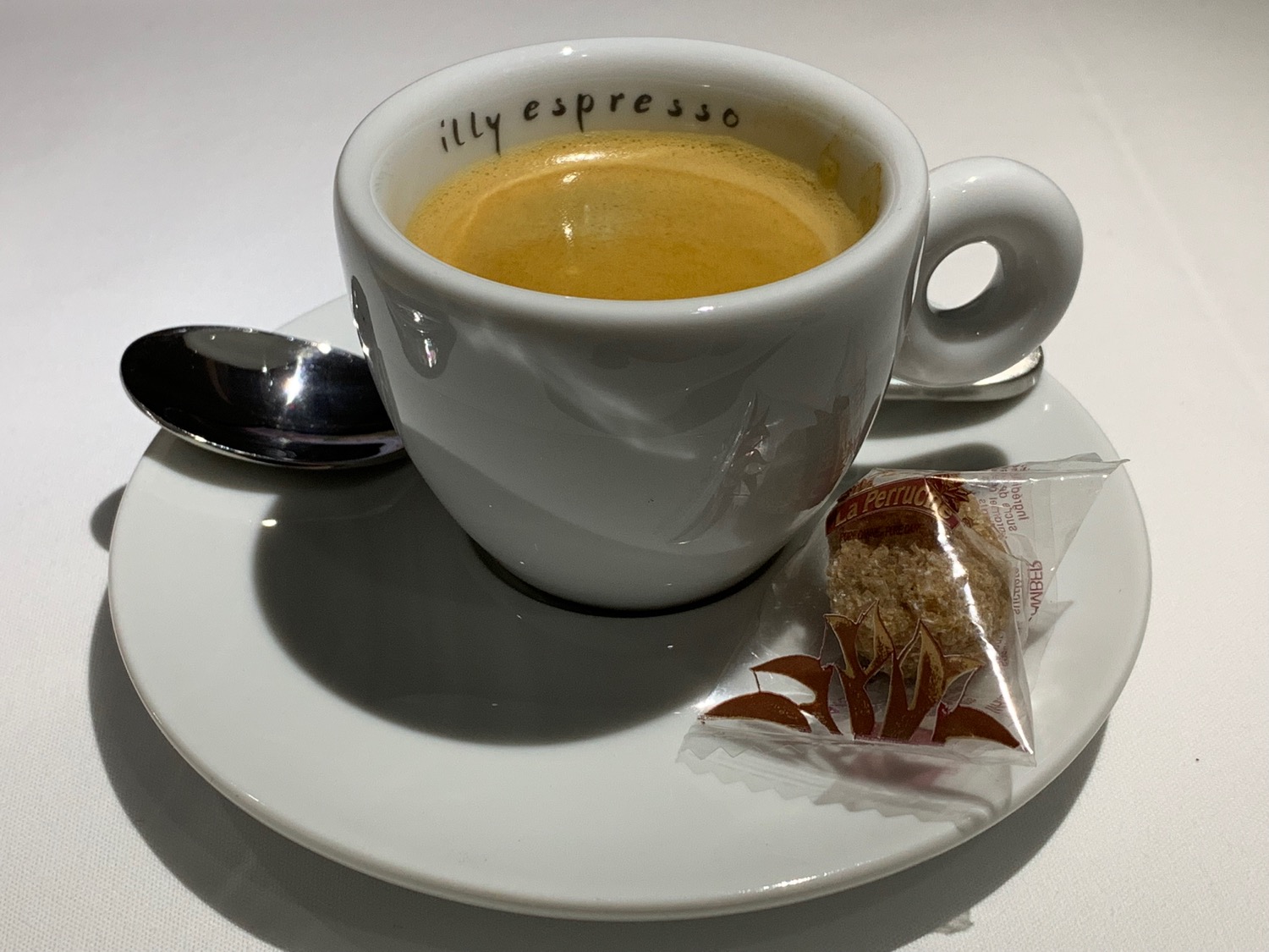 a cup of coffee on a saucer with a spoon and a bag of brown sugar
