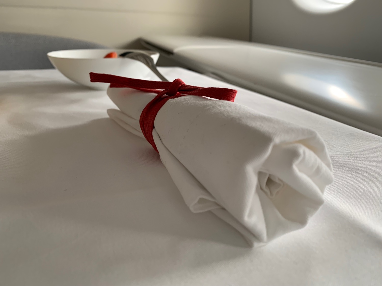 a white napkin tied with a red ribbon on a table