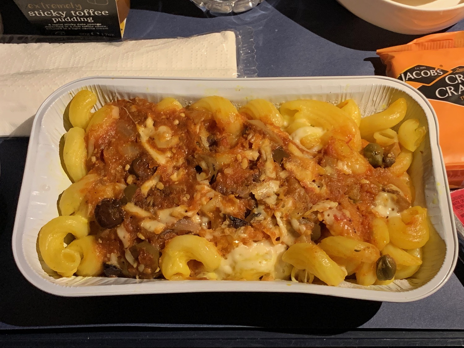 a tray of pasta with sauce and capers