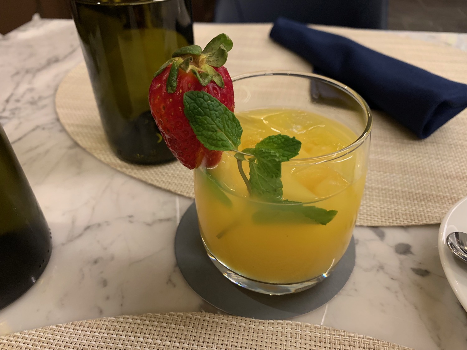 a glass of yellow liquid with a strawberry on top
