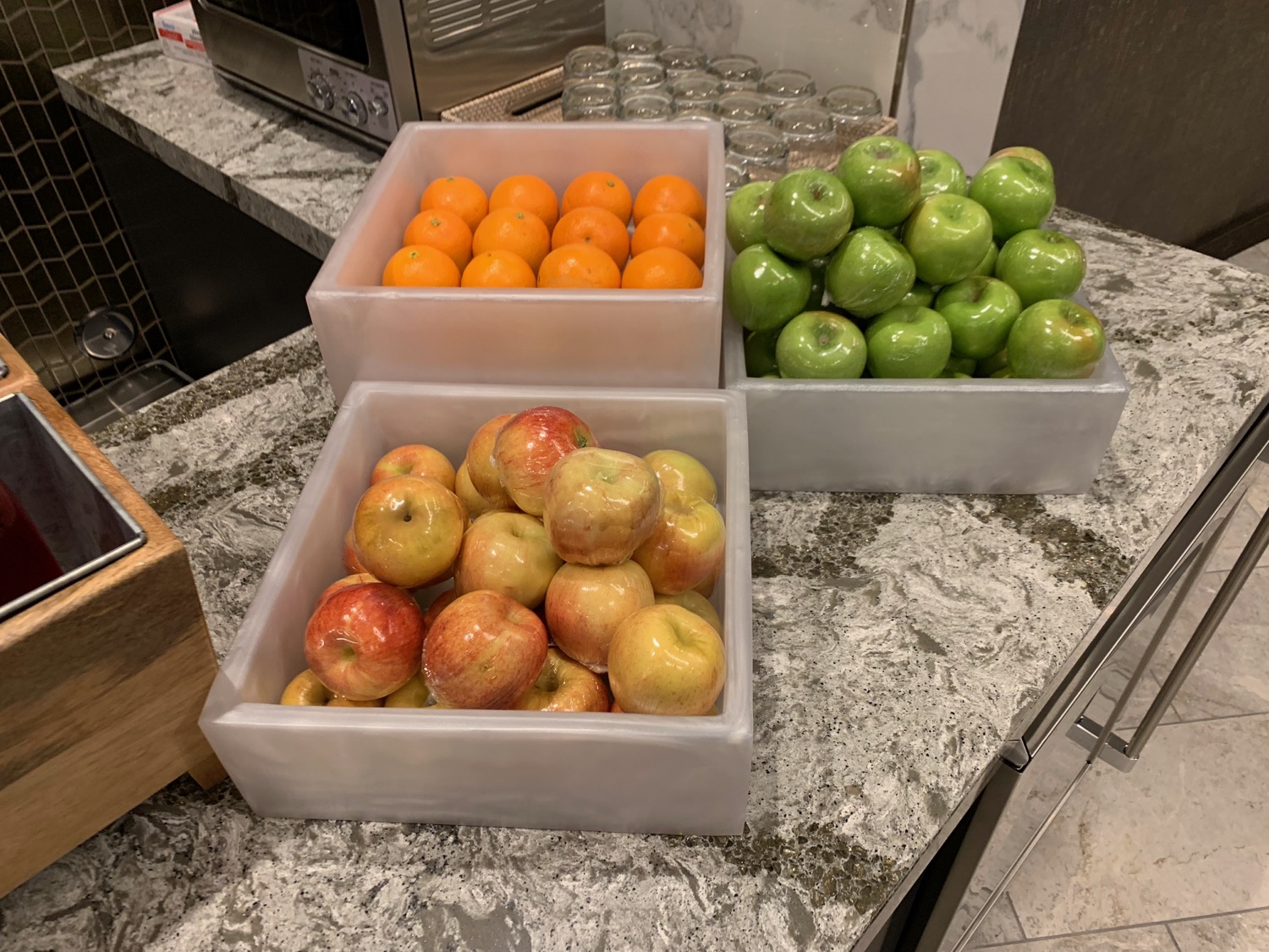 a group of containers of apples and oranges on a counter