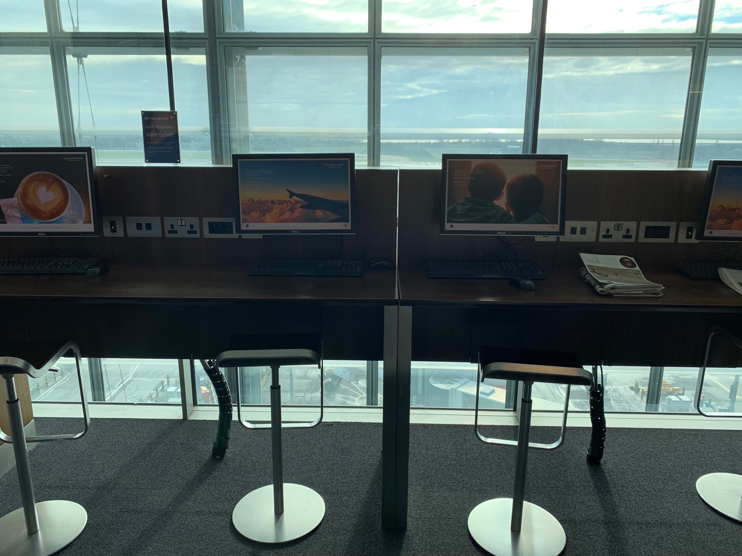 a desk with computers and stools in front of a window