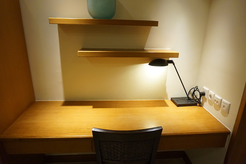 a desk with a lamp and shelves on the wall