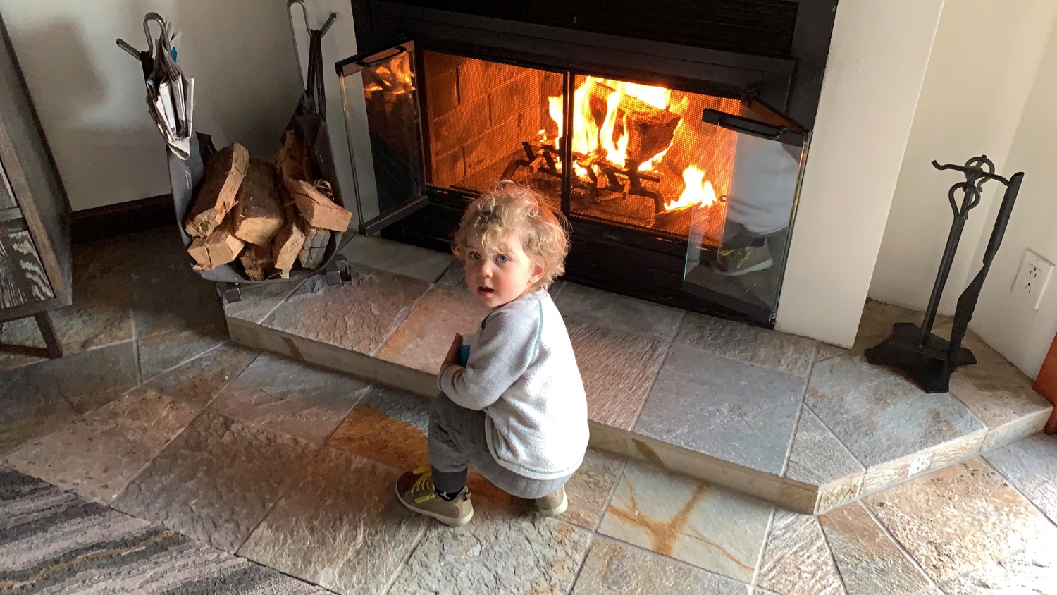 a child squatting in front of a fireplace
