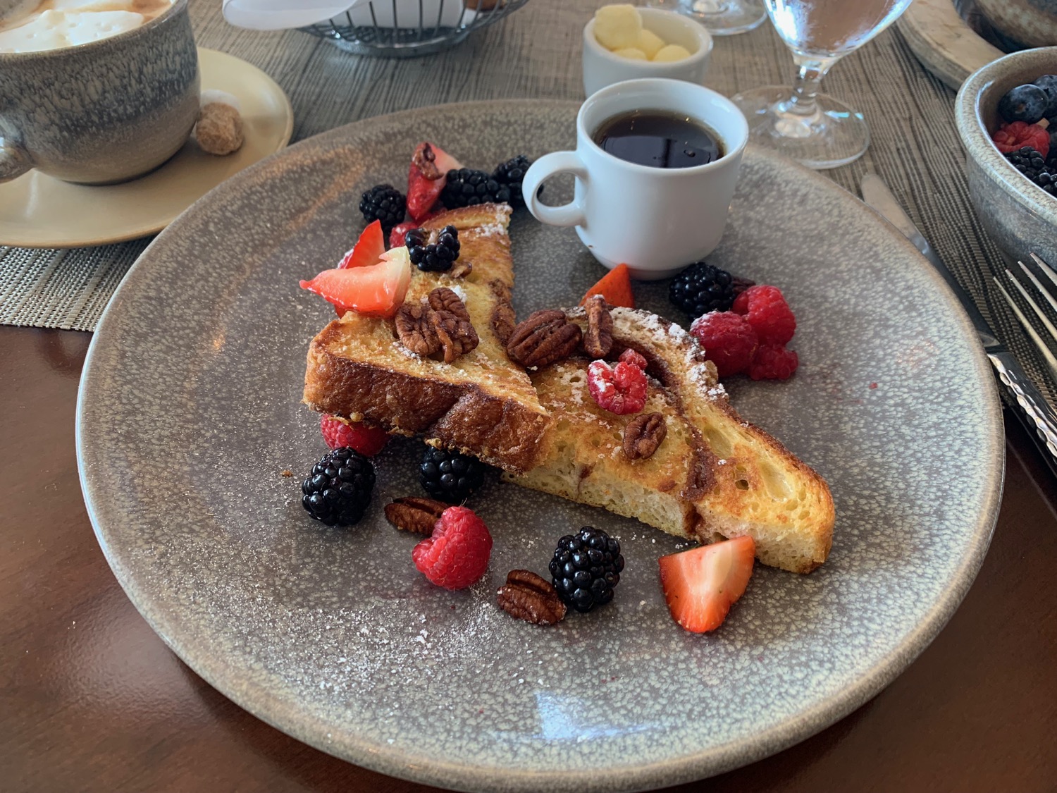 a plate of french toast with berries and coffee