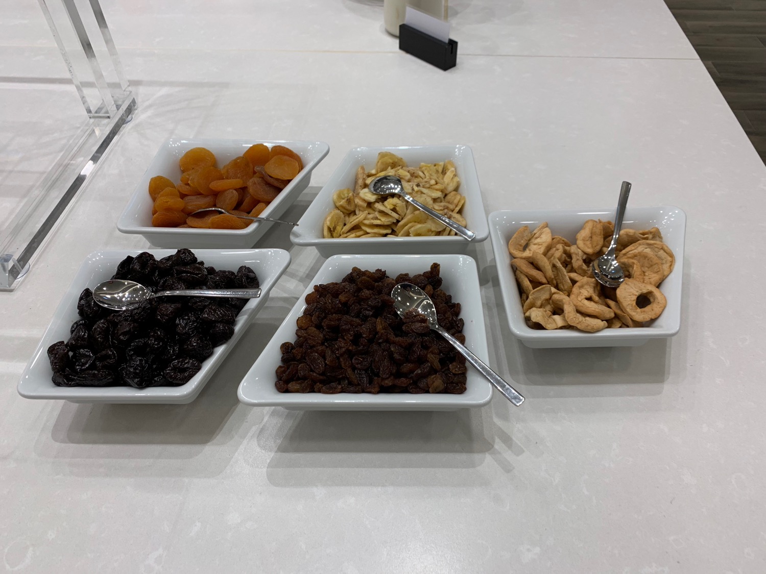a group of white rectangular bowls with different types of dried fruits