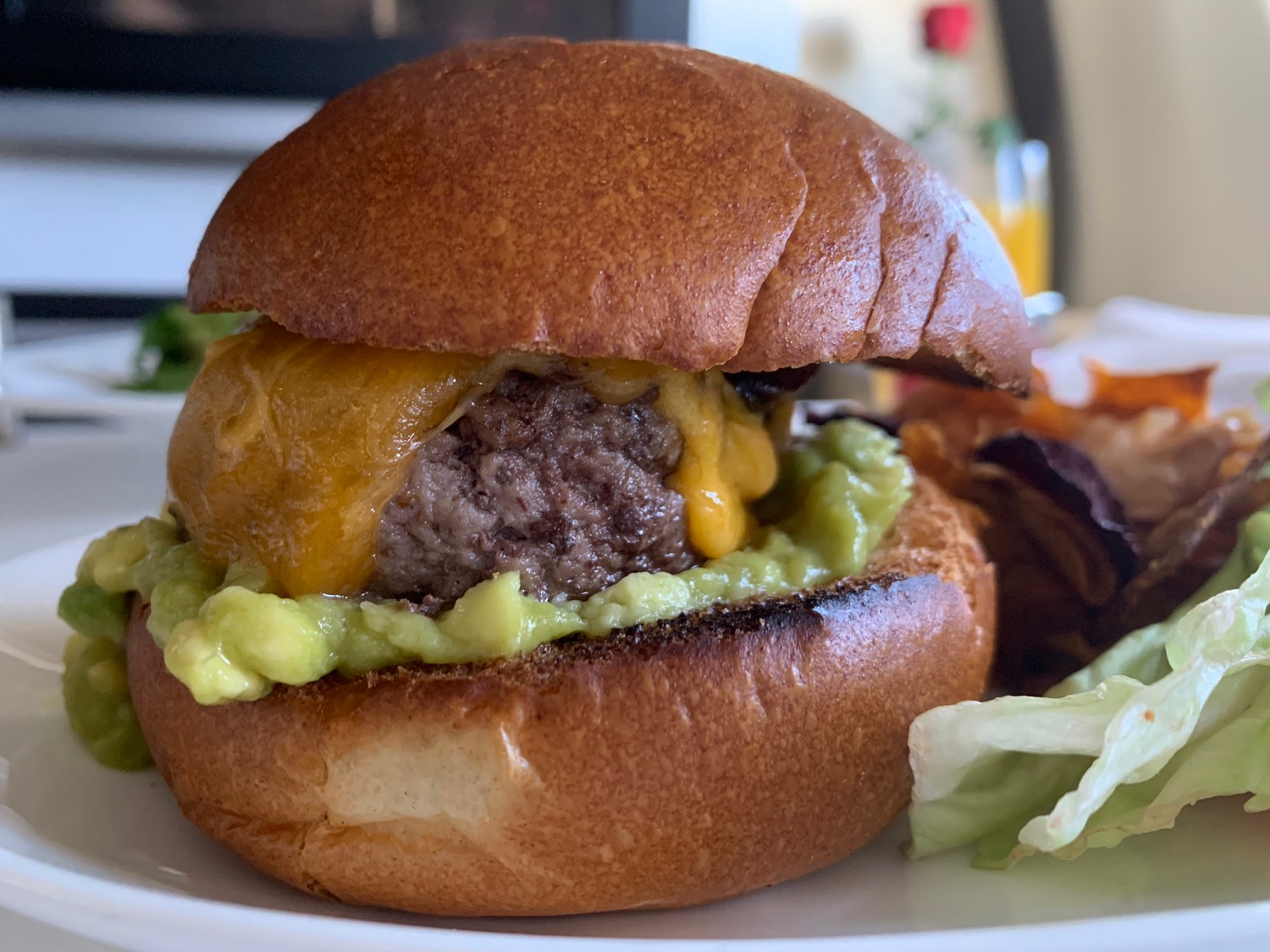 a burger with cheese and guacamole on a plate
