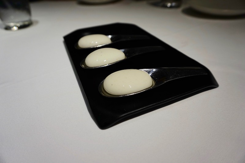spoons with white food on them on a black tray