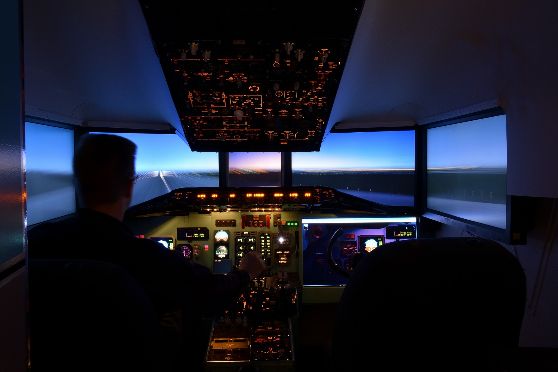 a man in a cockpit with a large screen and a large window