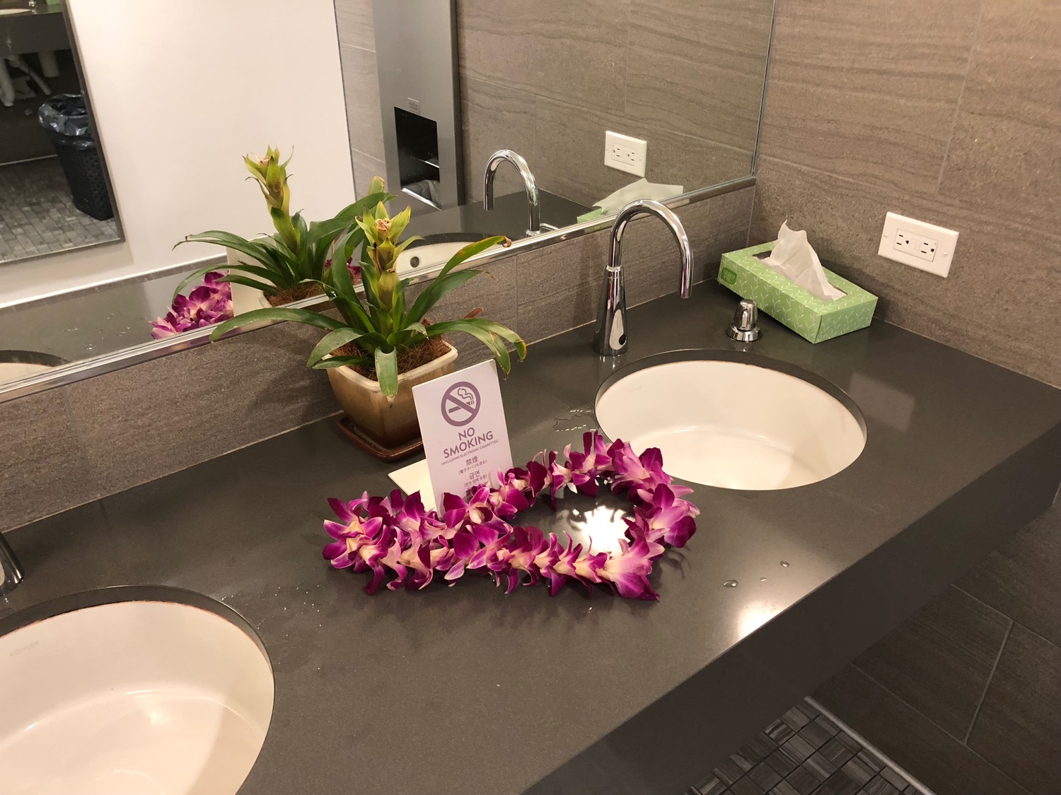 a bathroom sink with purple flower garland on it