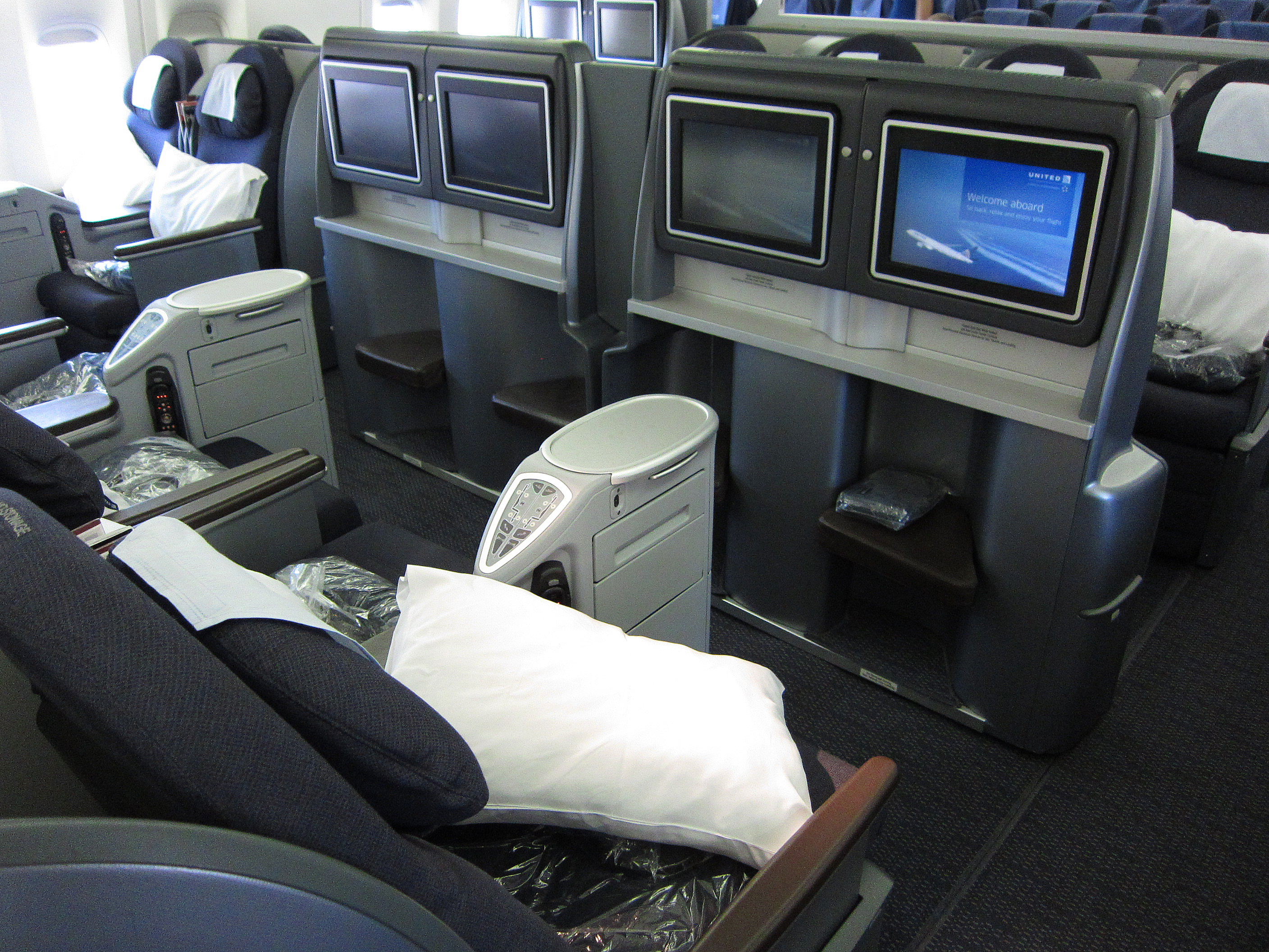 a seat in an airplane with a white pillow and a white pillow