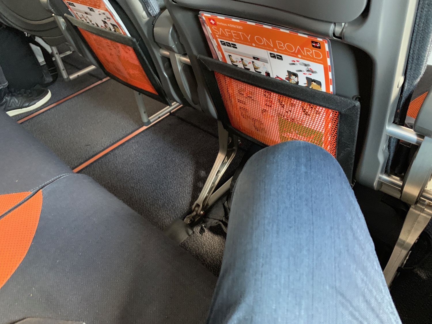 a person's leg in a seat with safety signs in the back of the seat