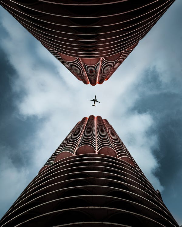 a plane flying in the sky above a tall building
