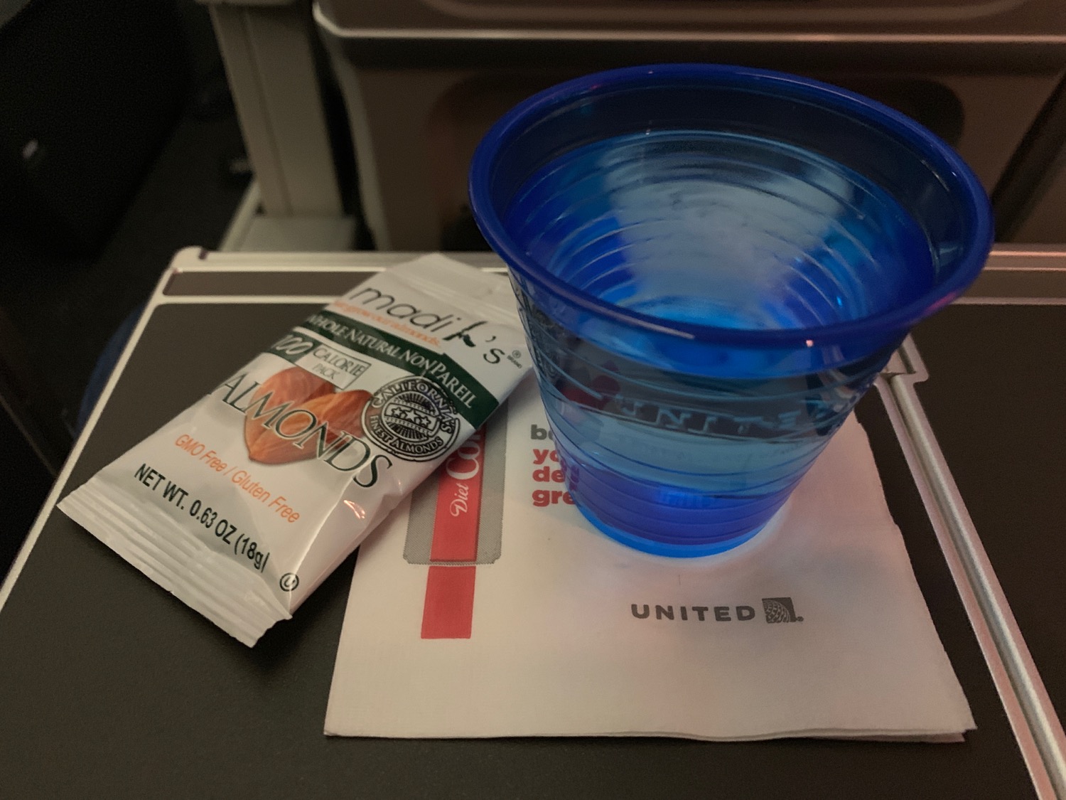 a blue plastic cup and a packet of almonds on a white napkin