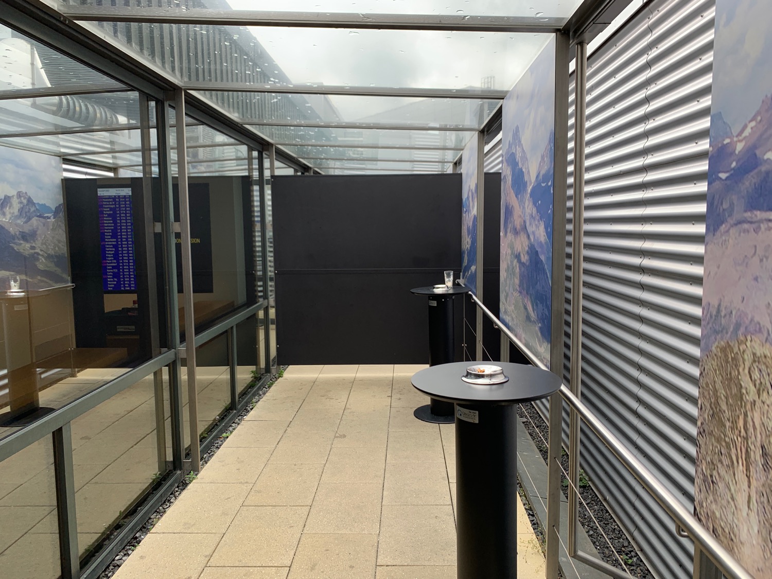 a glass covered walkway with a table and a poster