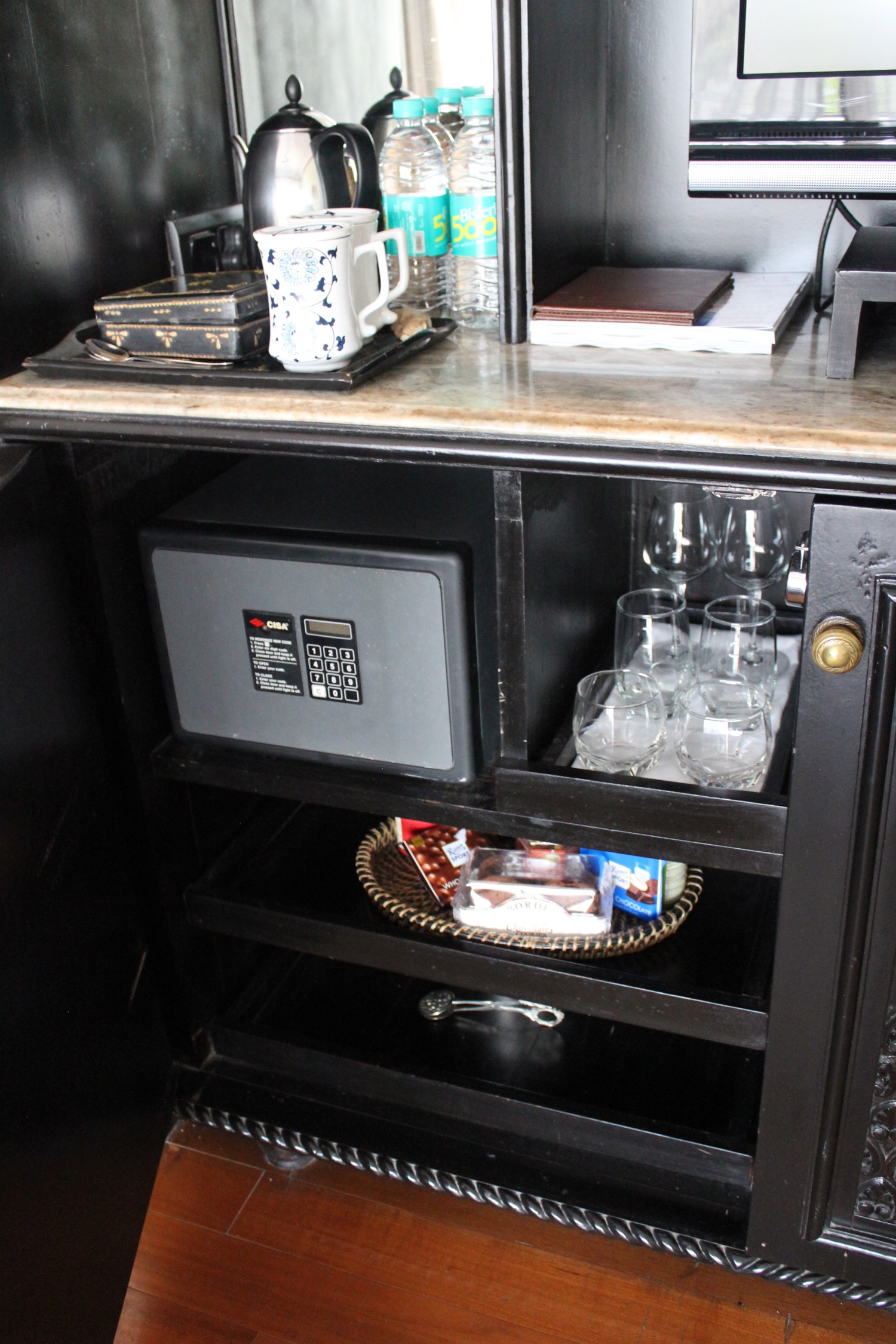 a black cabinet with a safe and glasses on it