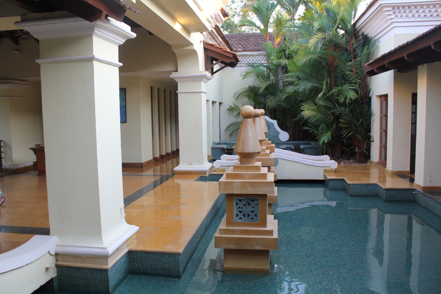 a pool with columns and a building with palm trees