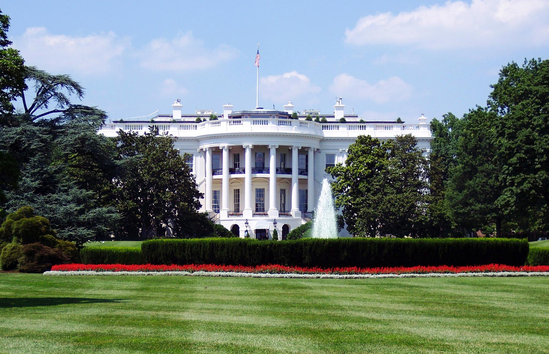 a white house with columns and a fountain in front with White House in the background