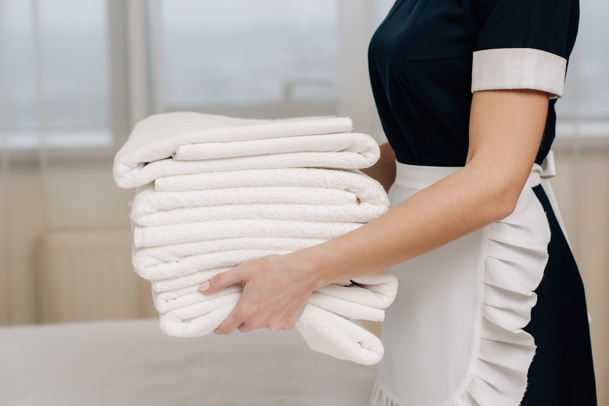 a maid holding a stack of towels
