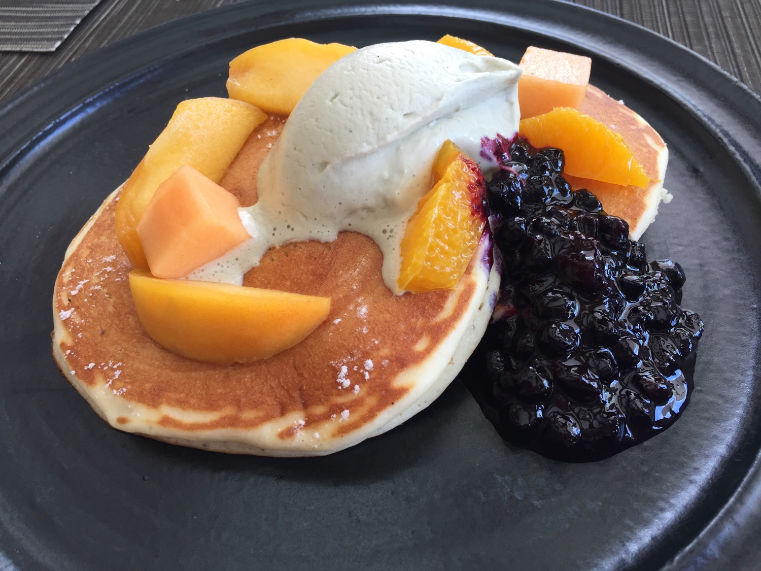 a plate of pancakes with fruit and ice cream