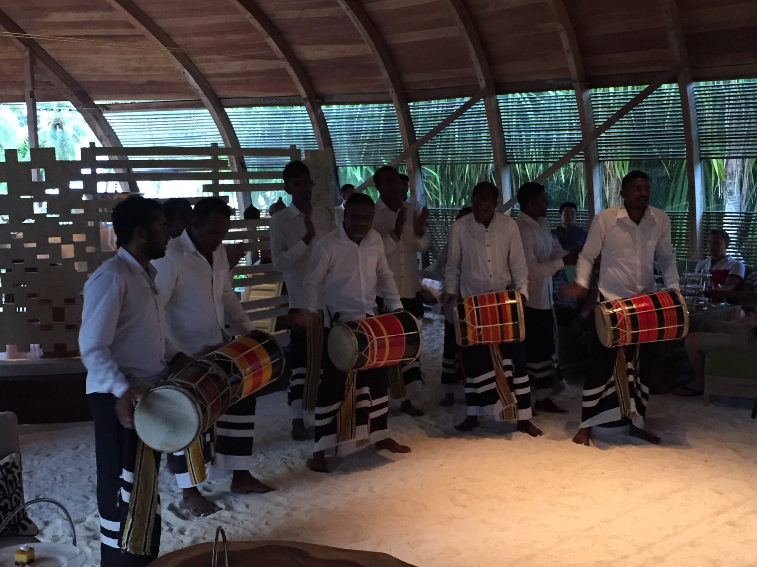 a group of men in white shirts holding drums