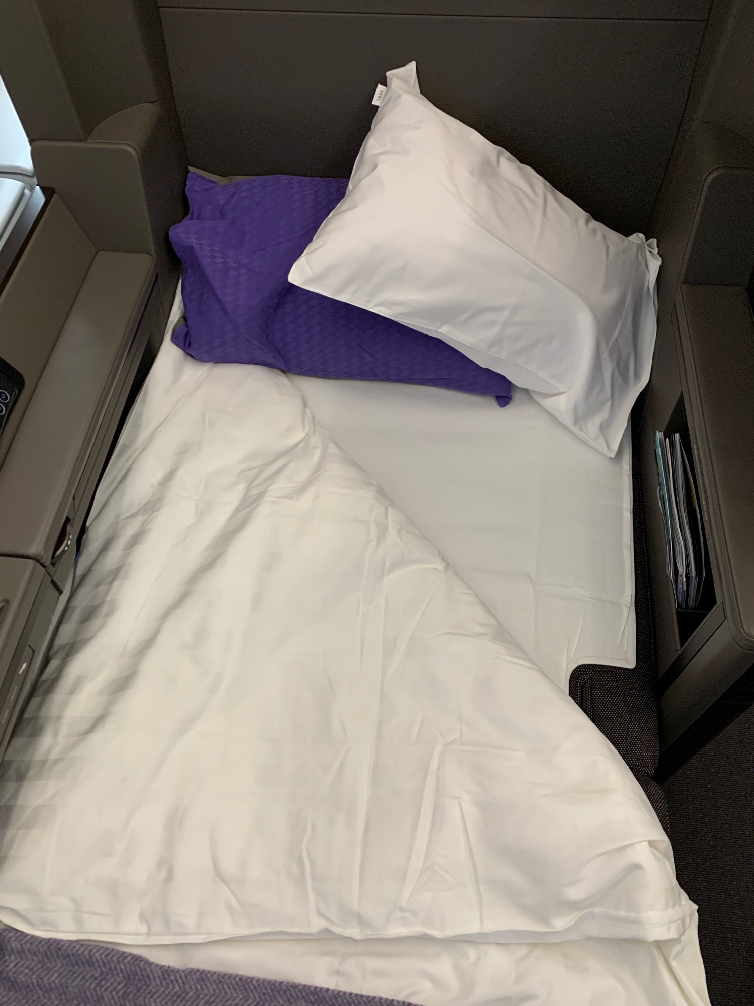 a bed with pillows and a purple pillow on it
