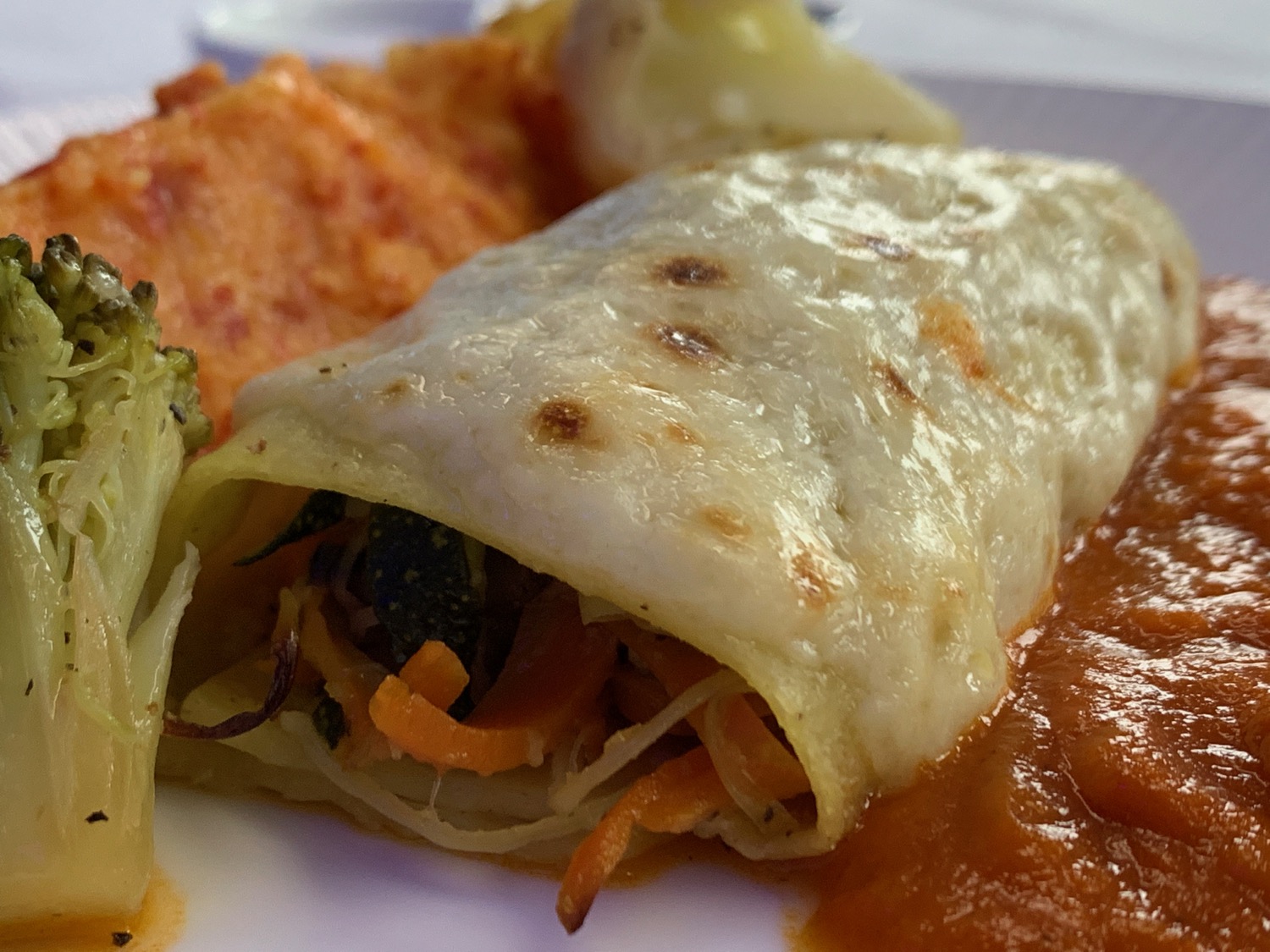 a burrito with vegetables and sauce on a plate