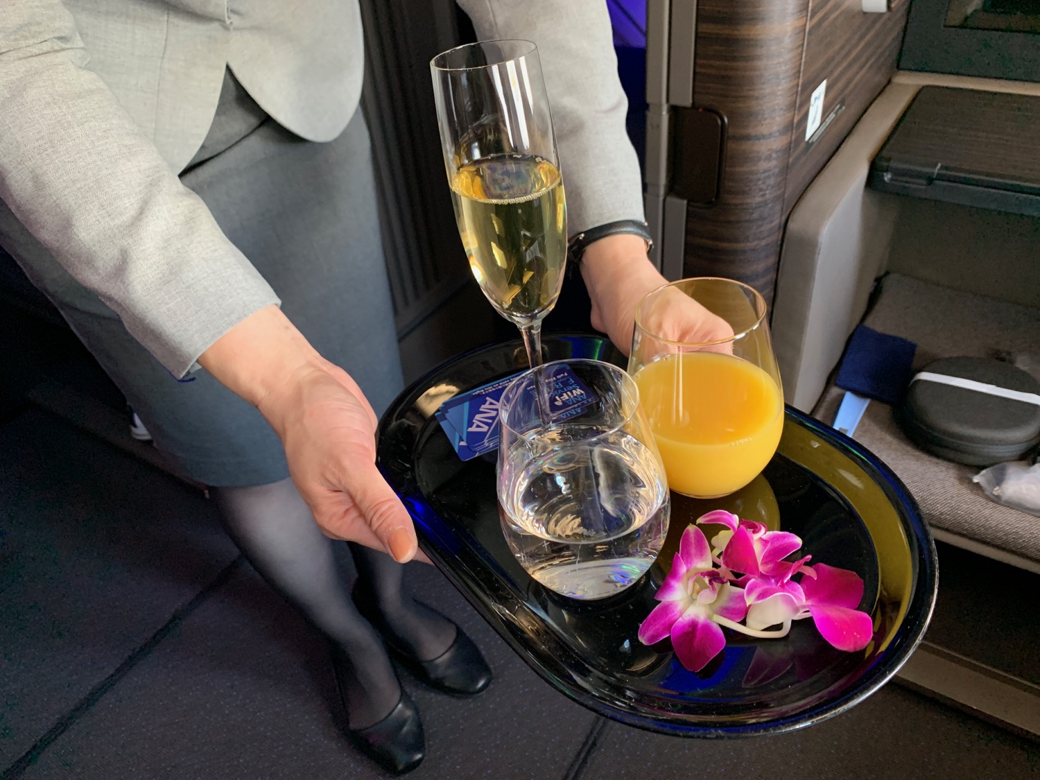 a person holding a tray with glasses of champagne and orange juice