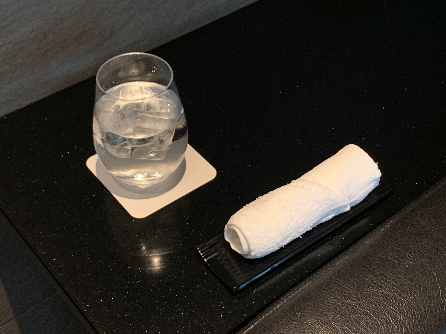 a glass of water and a rolled up towel on a black surface