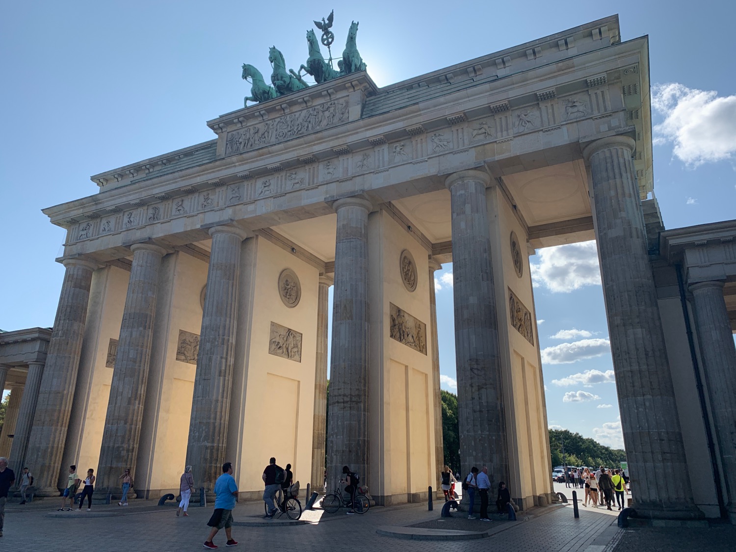 a large stone structure with columns and statues on top with Brandenburg Gate in the background