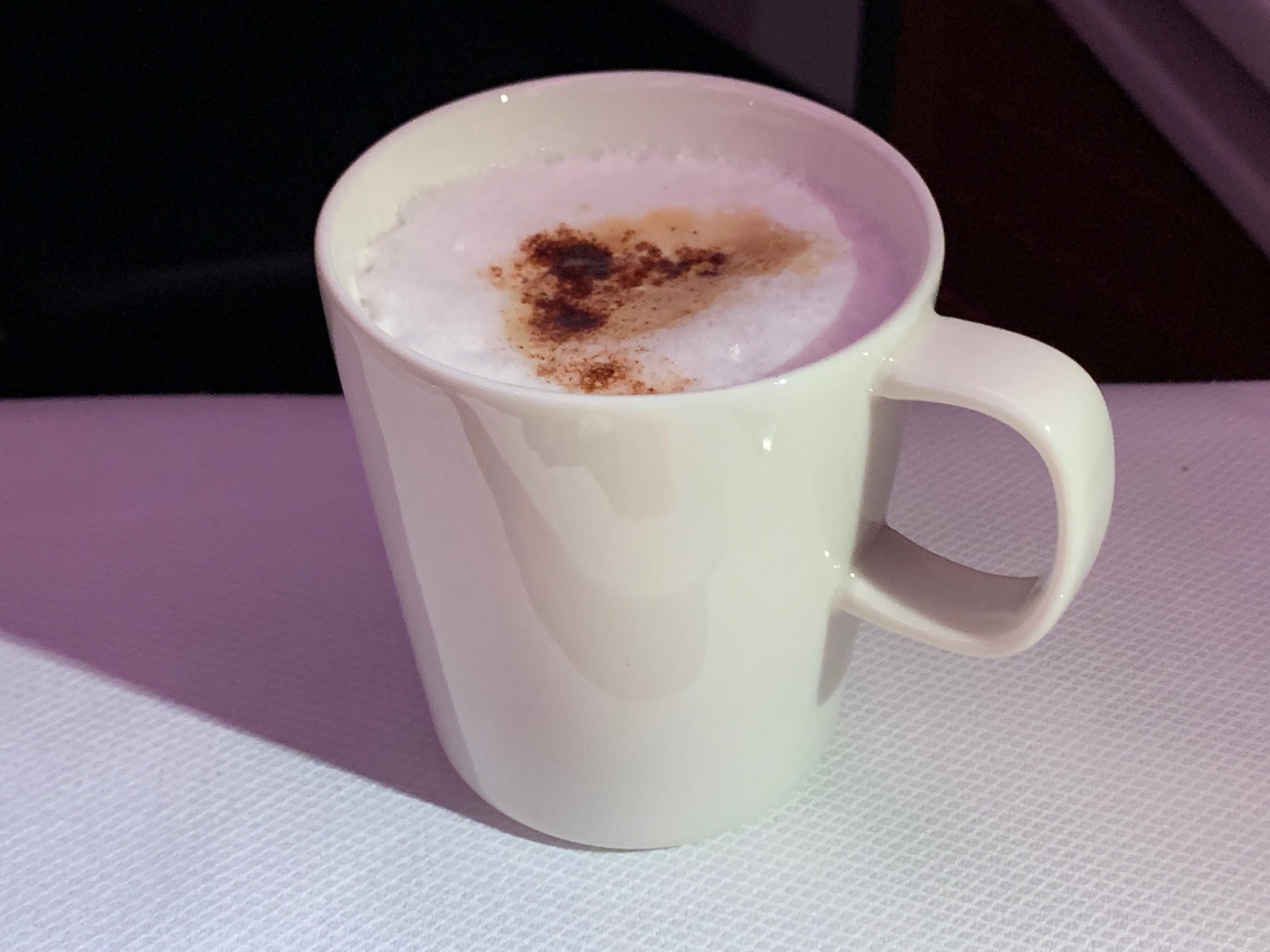 a white mug with a brown foamy drink