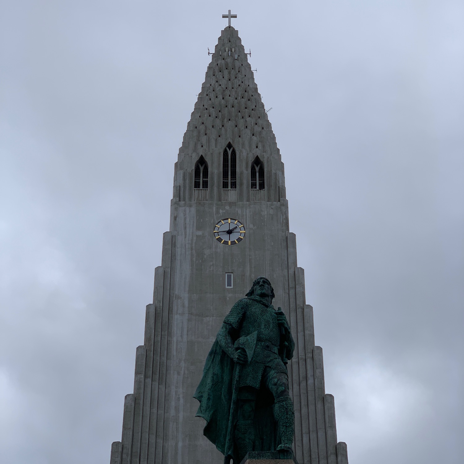 a statue of a man in front of a tall building with Hallgrímskirkja in the background