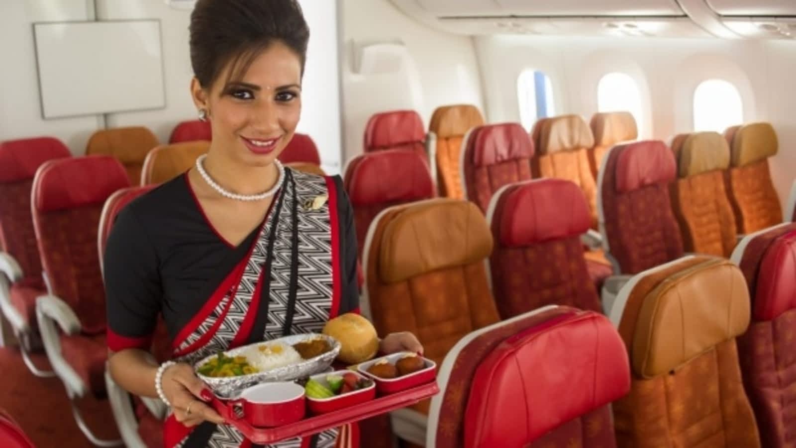 a woman holding a tray of food in an airplane