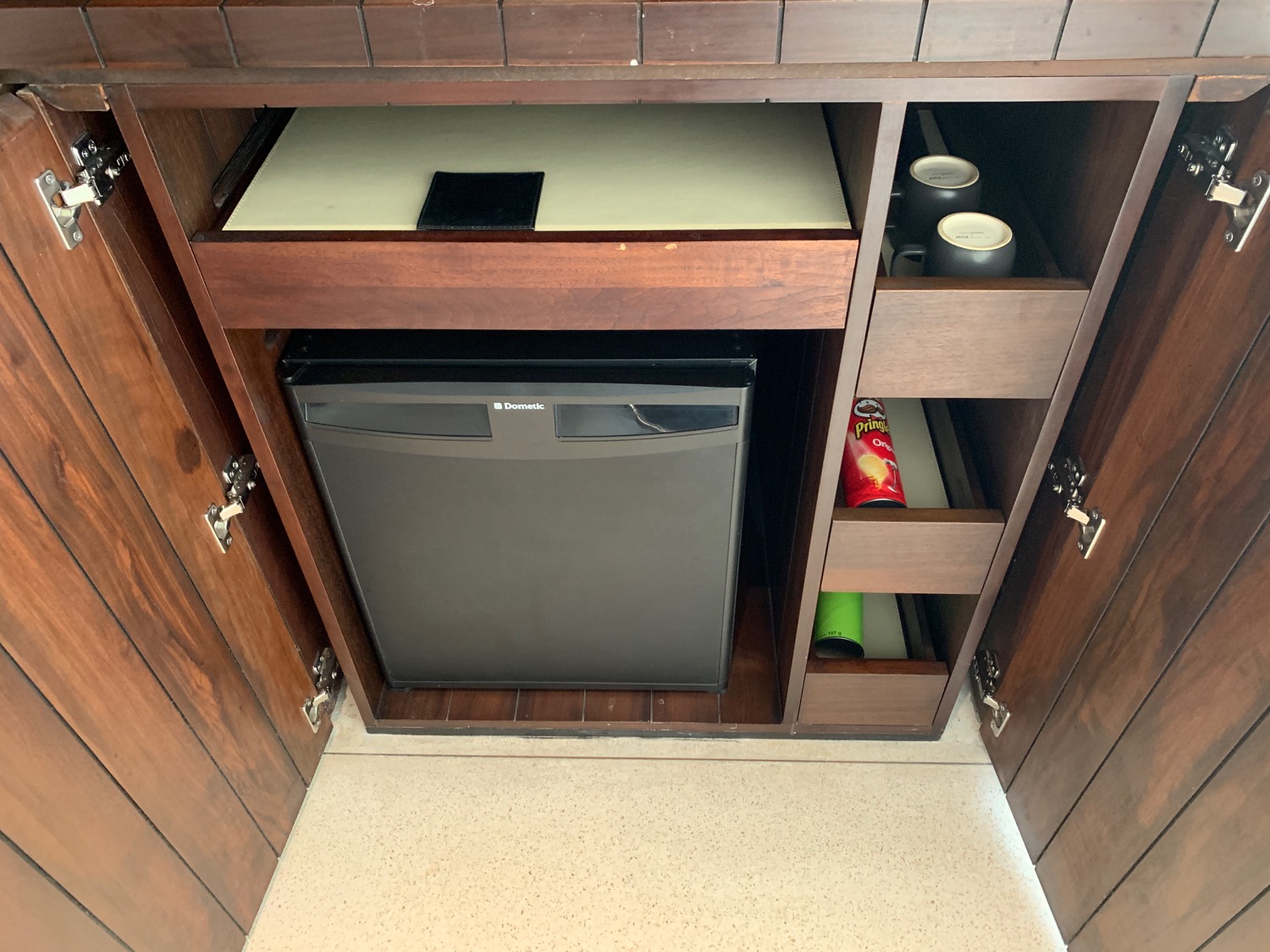 a small black refrigerator in a wooden cabinet