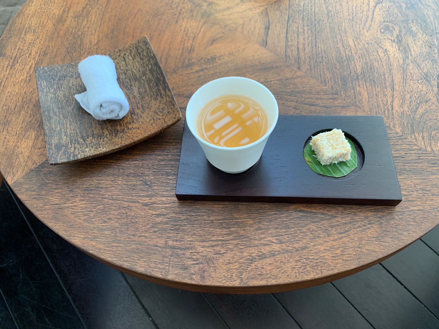 a cup of liquid and a towel on a wooden tray