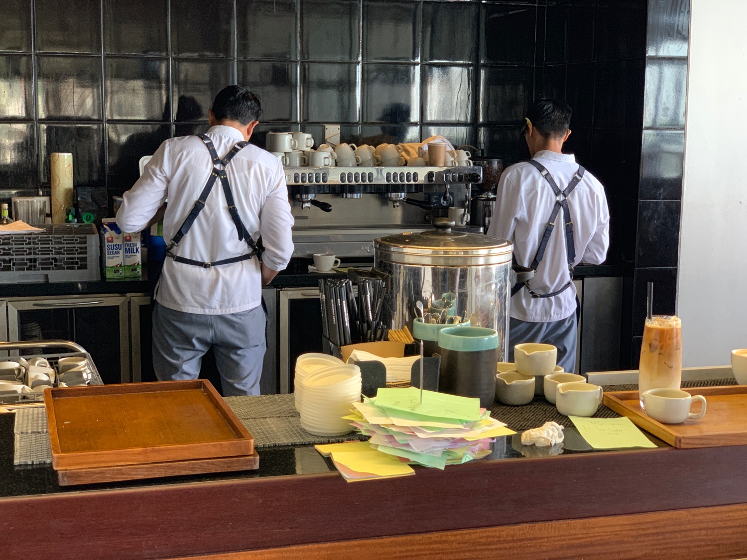 two men in white uniforms working at a coffee machine
