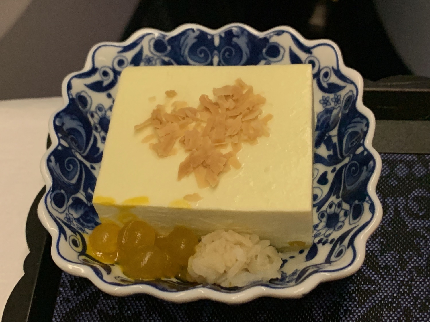 a white square with yellow flakes on top of a blue and white floral bowl