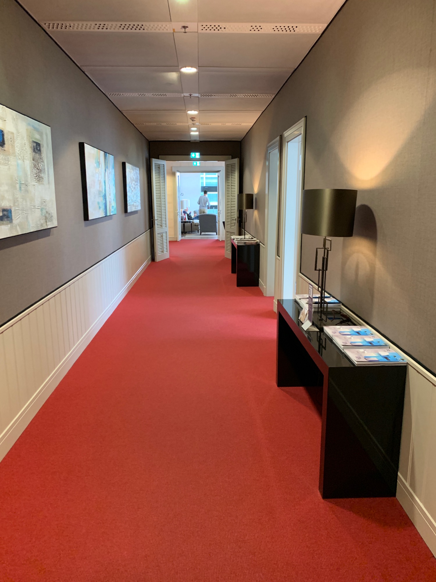 a hallway with red carpet and a black table