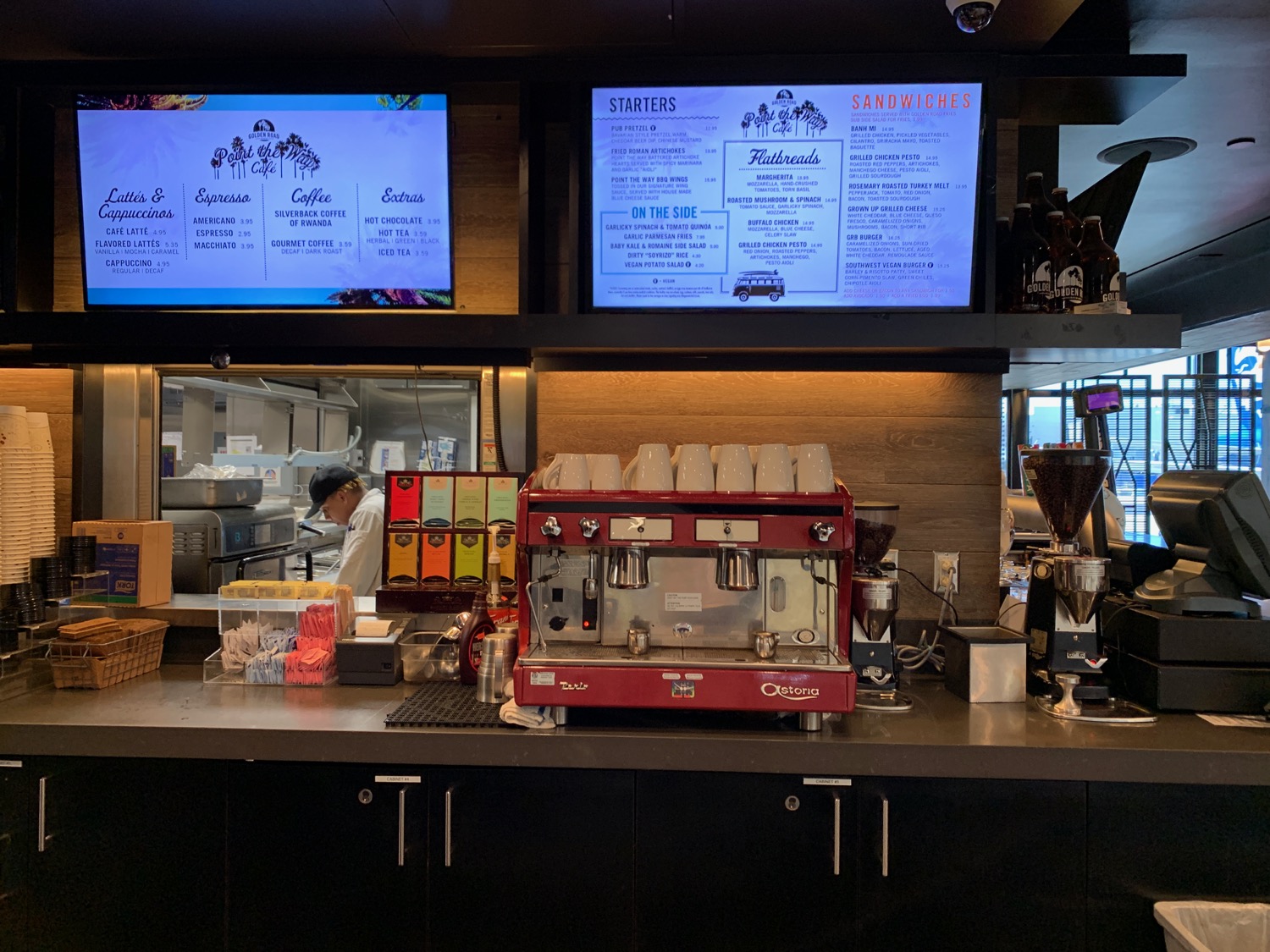 a coffee machine and a counter with several screens on the wall