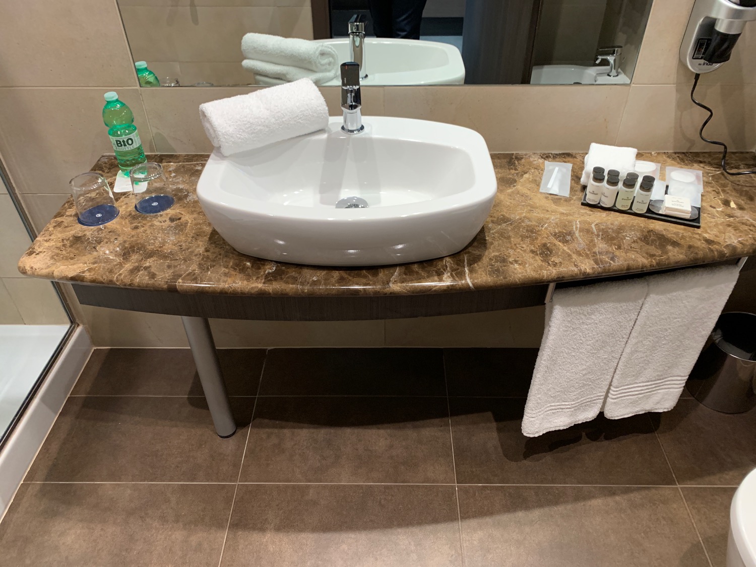 a sink with towels and bottles on a marble counter