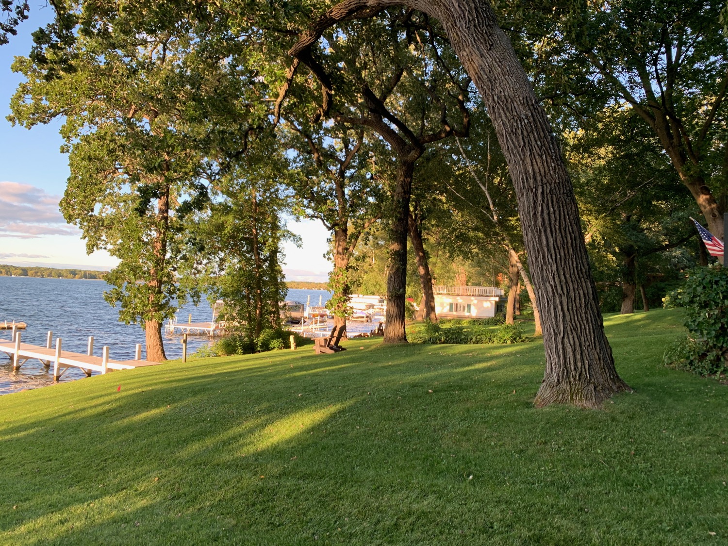 a grass field with trees and a dock in the background