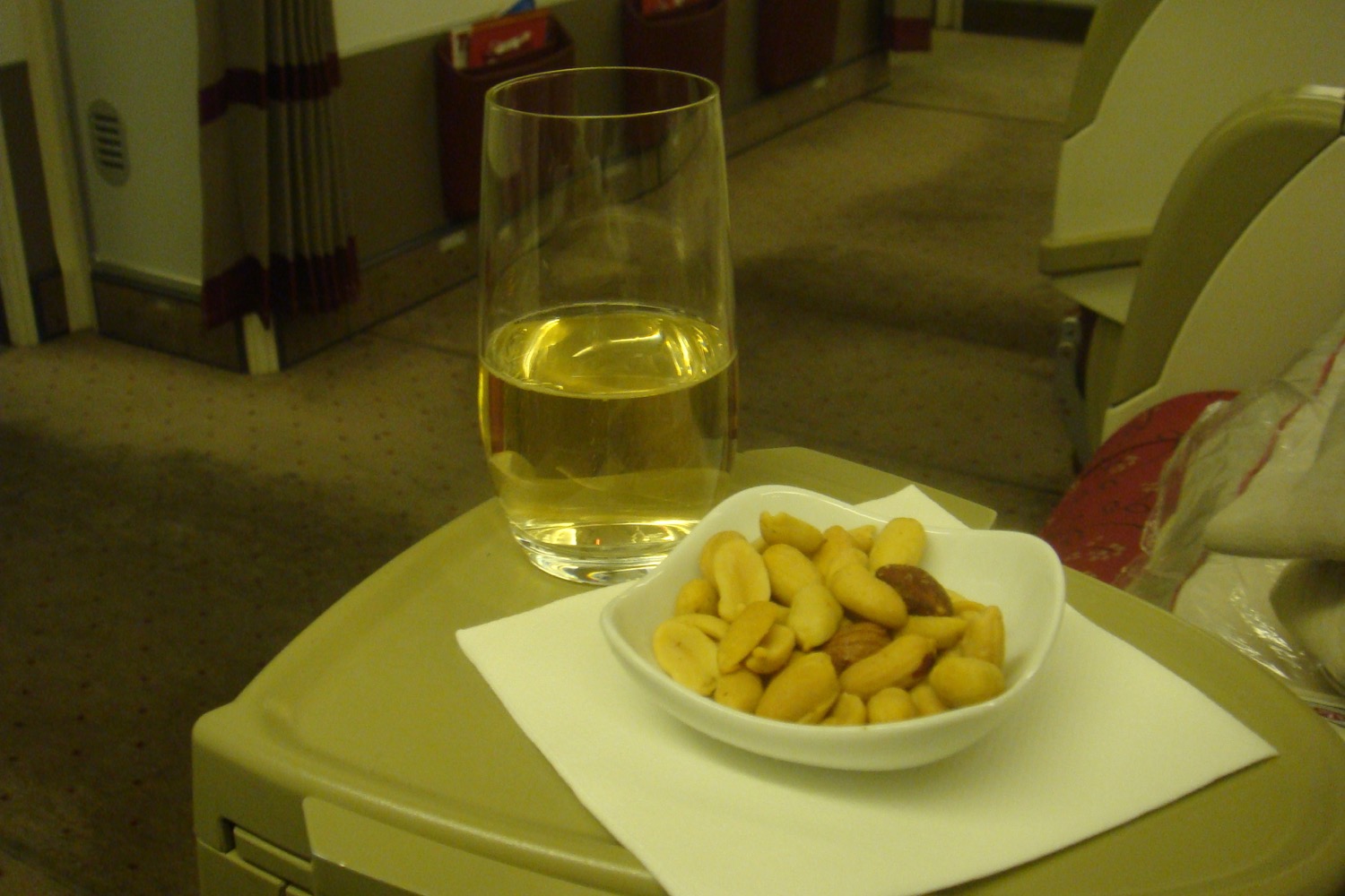 a bowl of nuts and a glass of liquid on a tray