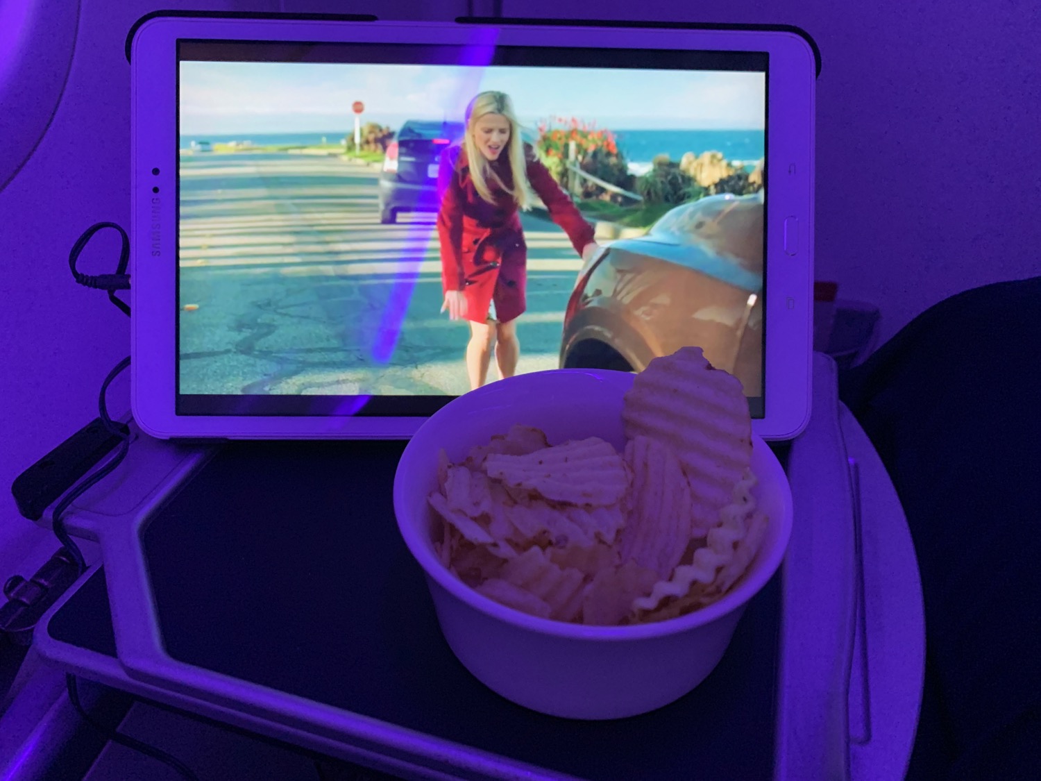a tablet with a bowl of potato chips and a woman on the screen