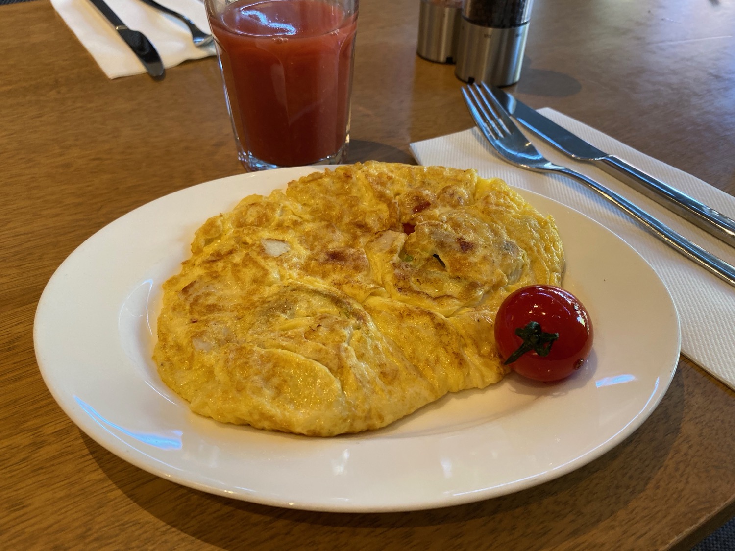 a plate of omelette with a cherry tomato on it