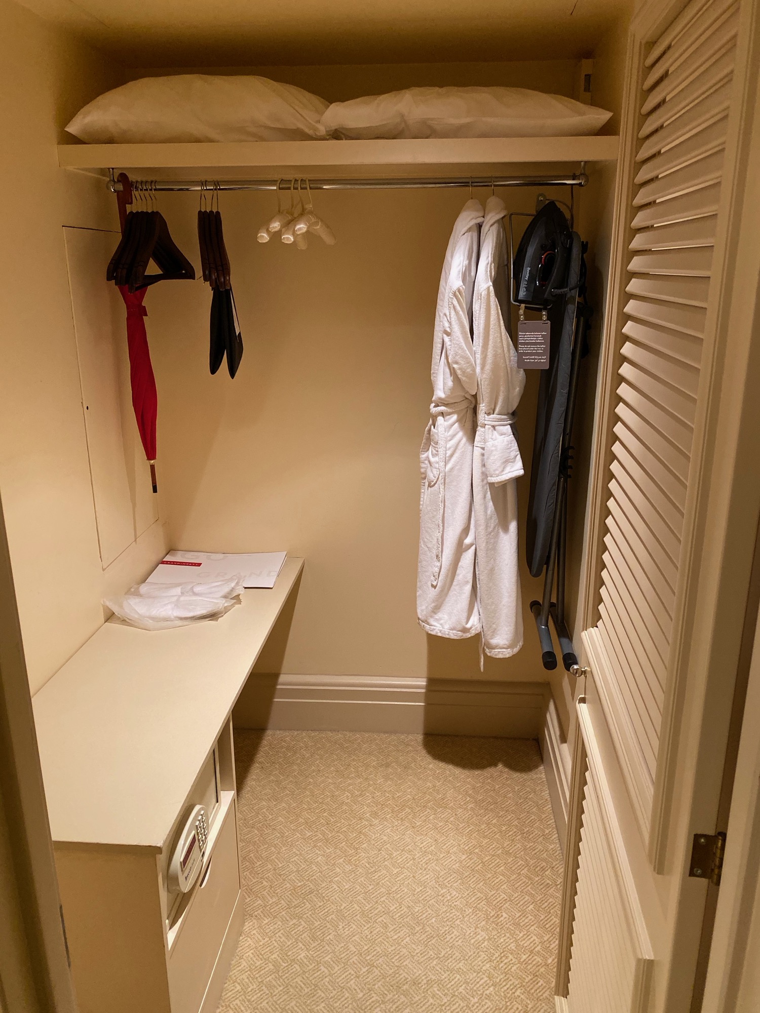 a closet with white robe and clothes from it