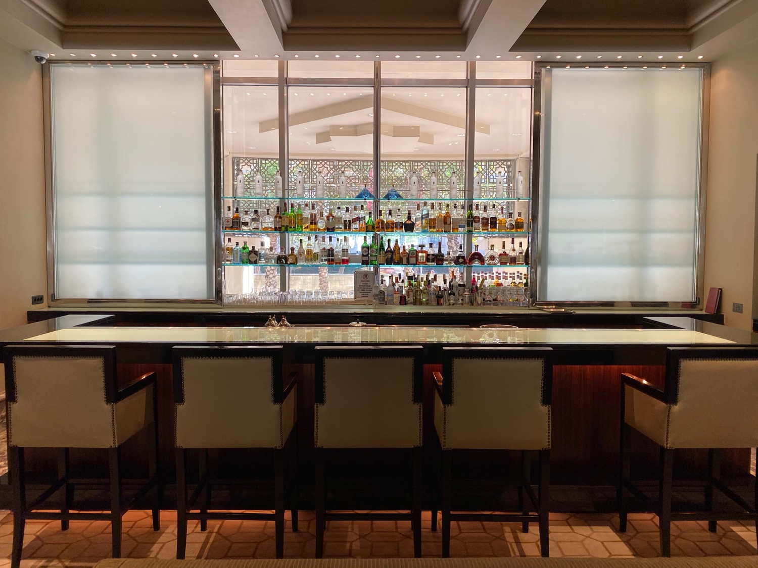 a bar with a row of chairs and bottles